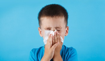 sick child blowing his nose