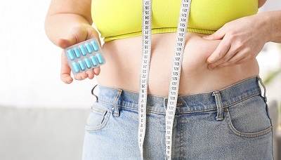 Overweight woman holding pills