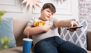 Picture of obese child watching TV and eating