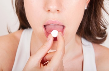 woman placing tablet on her tongue